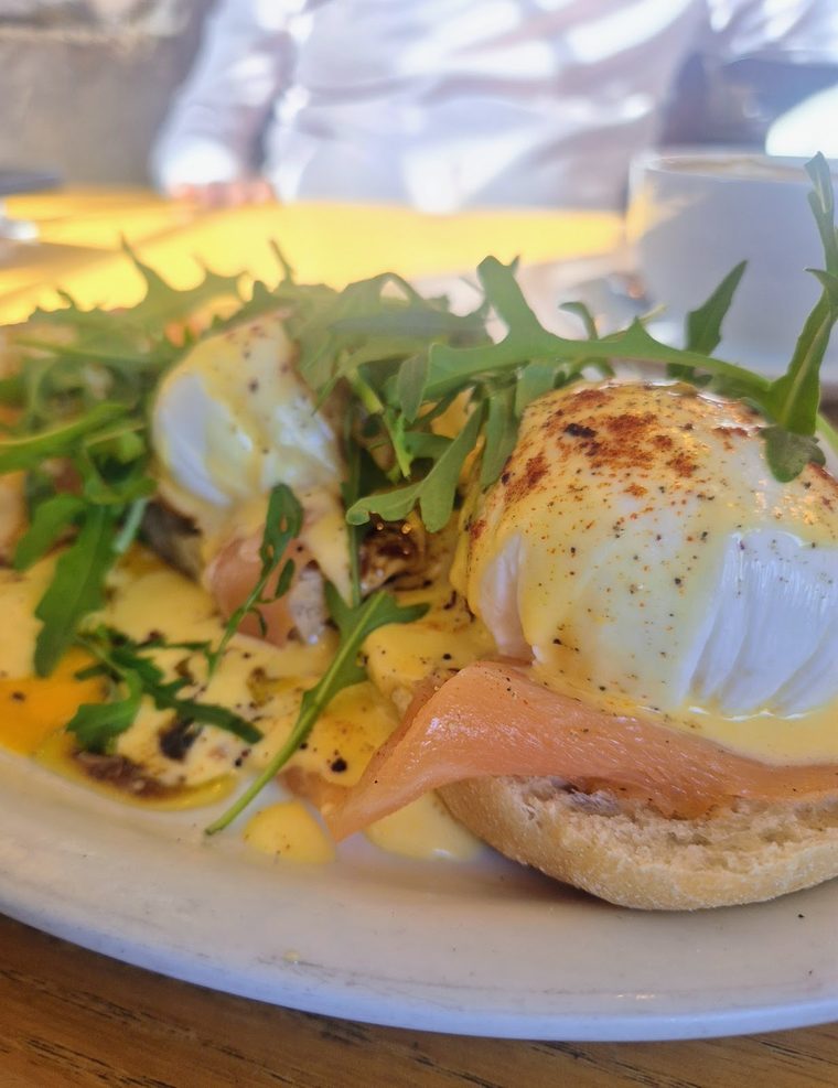 Close view of smoked salmon eggs benedict with a runny poached egg and rocket