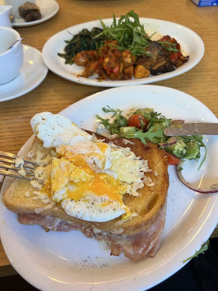 Poached egg on toasted sourdough with ham and avocado on a wooden table